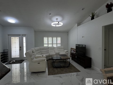 A living room with a white sofa set and a television.