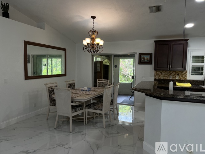 A dining room with a table set for four and a chandelier hanging from the ceiling.