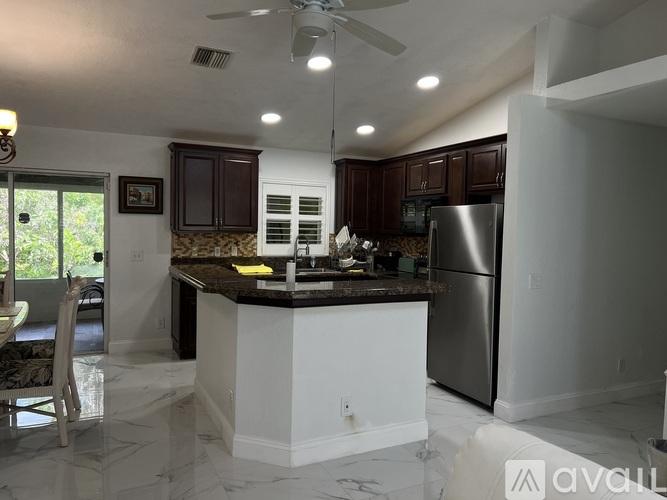 A kitchen with a white island and a stainless steel refrigerator.