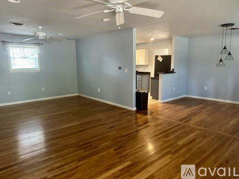A spacious room with wooden flooring and a ceiling fan.