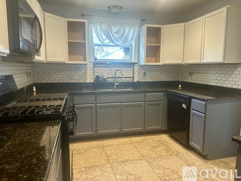 A kitchen with a black stove top and white cabinets.