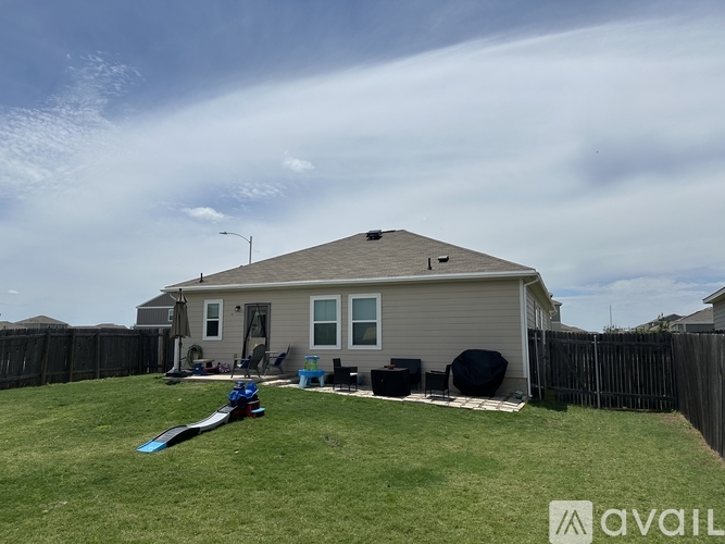 A house with a grey roof and a black trampoline in the yard.
