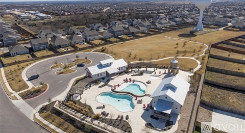 A bird's eye view of a residential area with a park and a pool.