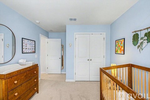 A bedroom with a white bed and a wooden dresser.
