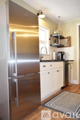 A kitchen with a stainless steel refrigerator and white cabinets.