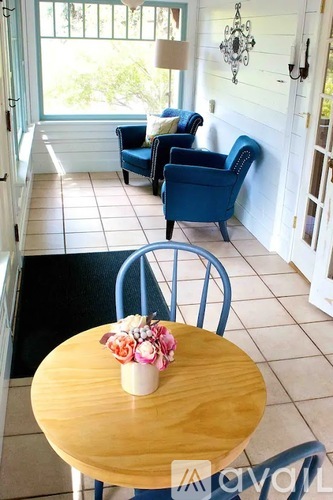 A table with flowers on it sits in front of two chairs.