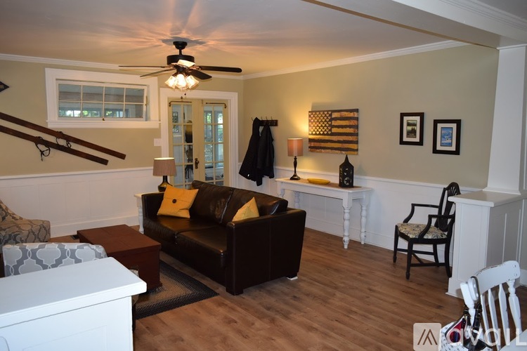 A living room with a brown couch and a ceiling fan.