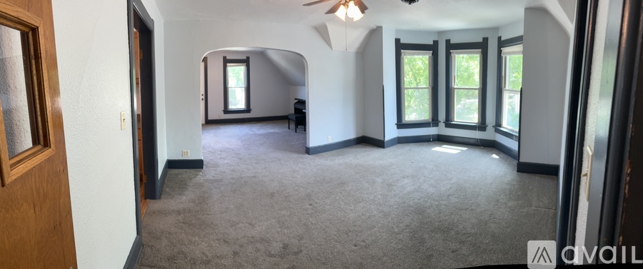 A spacious room with a ceiling fan and large windows.