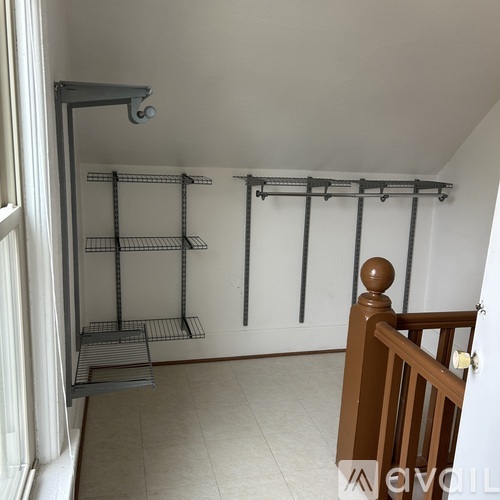 A room with a metal rack and a wooden staircase.