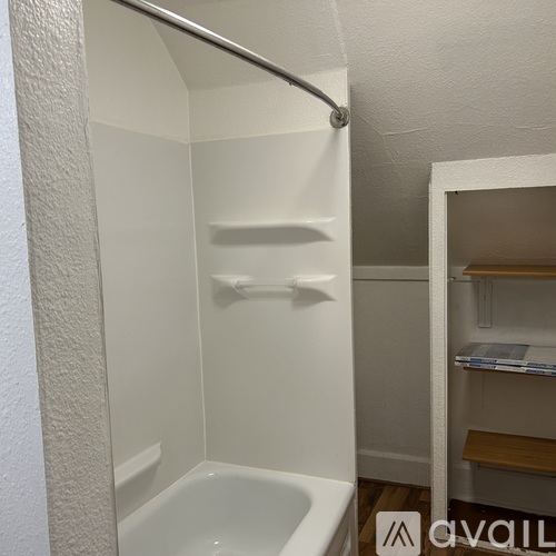 A white bathroom with a tub and shelves.