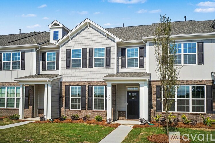 A two-story house with a front porch and a tree in front.