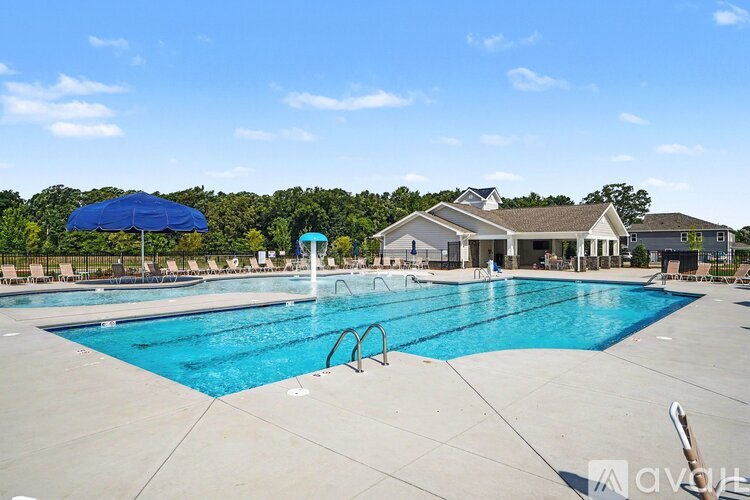 A large swimming pool with a diving board and a blue umbrella.