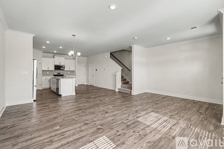 A spacious kitchen with white cabinets and a wooden floor.