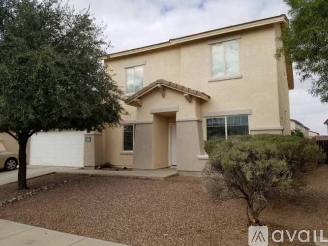 A beige house with a tree in front of it.