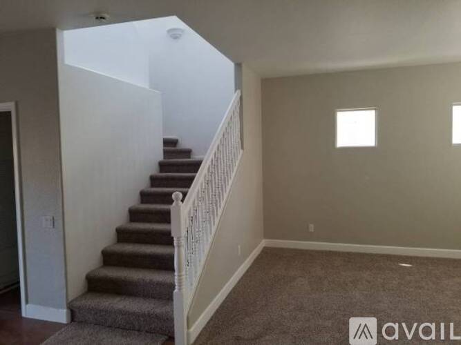 A staircase with a carpeted runner and white balusters leads up to a second floor.