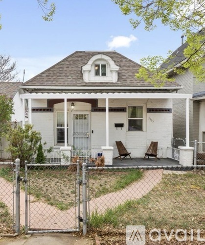 A white house with a porch and a fence in front.