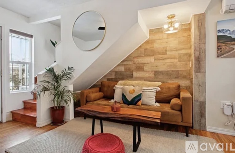 A living room with a couch, a plant, and a mirror on the wall.