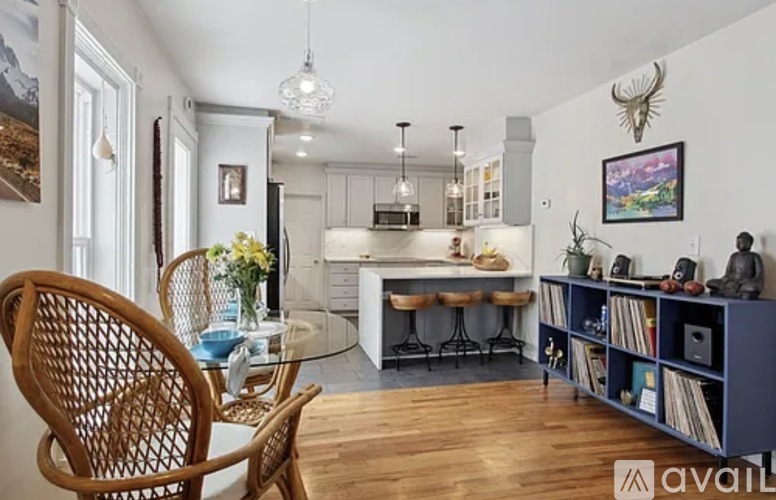 A dining room with a wooden chair and a table with a vase of flowers on it.