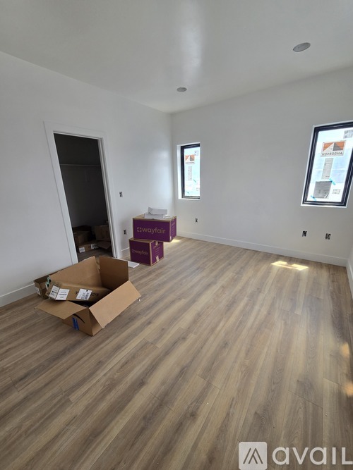A room with wooden flooring and a cardboard box on the floor.