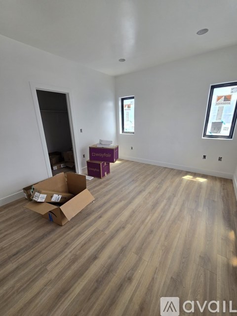 A room with wooden flooring and a cardboard box on the floor.