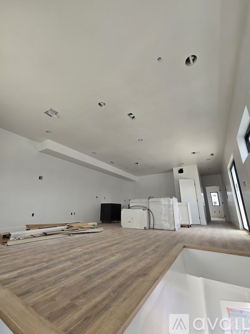 A room with wooden floors and white walls, with a few pieces of furniture and appliances.