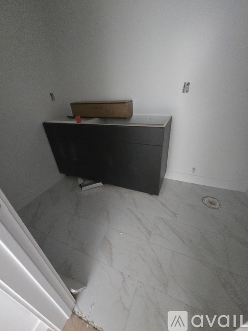 A bathroom with a black counter top and a white wall.