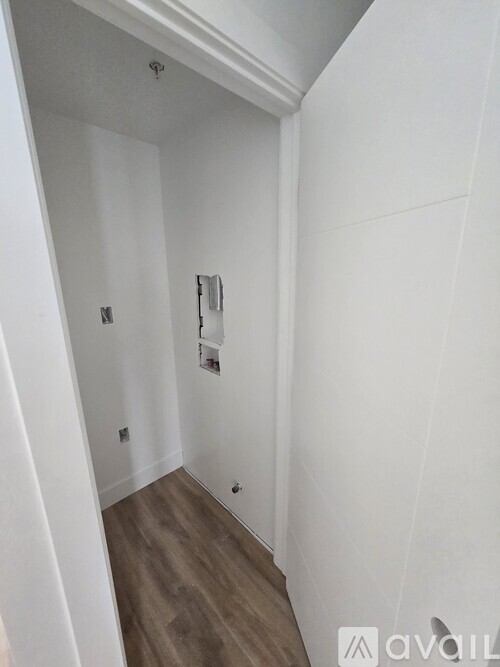 A white hallway with wood flooring and a white door.