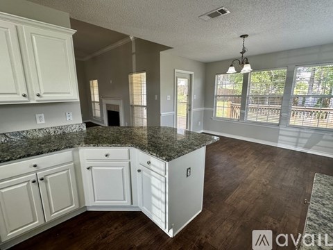 A kitchen with white cabinets and a granite countertop.