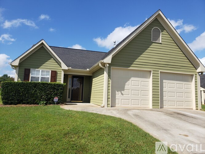 A house with a green siding and a grey roof with a white garage door.