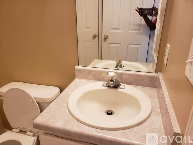 A bathroom with a toilet, sink, and mirror.