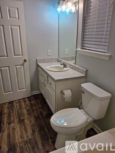 A bathroom with a toilet, sink, and mirror.