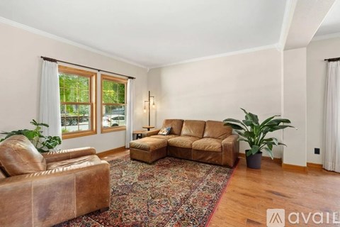 A living room with a brown leather couch and a rug.
