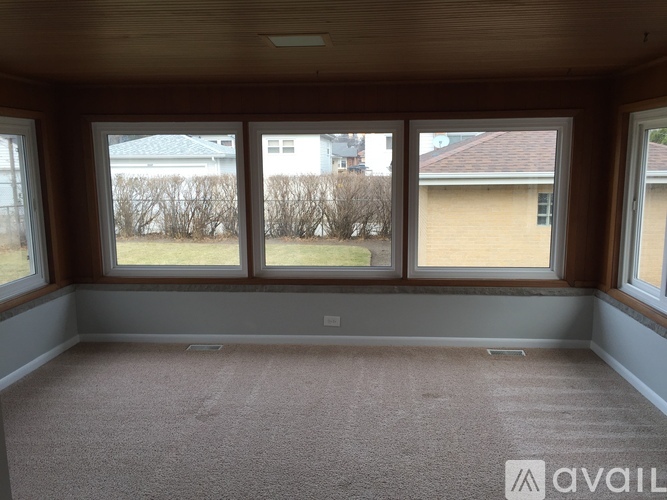 Empty room with three windows and carpeted floor.