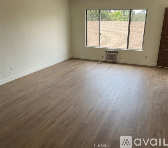A room with wooden flooring and a window with blinds.