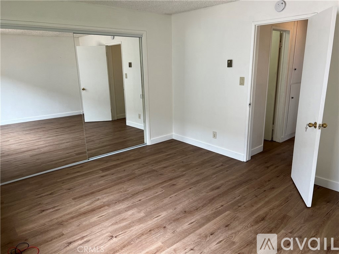 A room with wooden flooring and two doors, one of which is open.