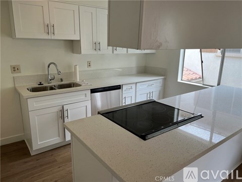 A kitchen with white cabinets and a black stove top.