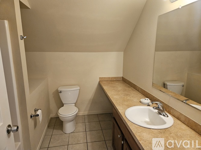 A bathroom with a toilet, sink, and mirror.