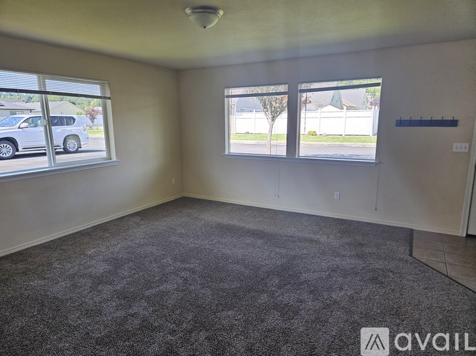 A room with a carpeted floor and two windows.