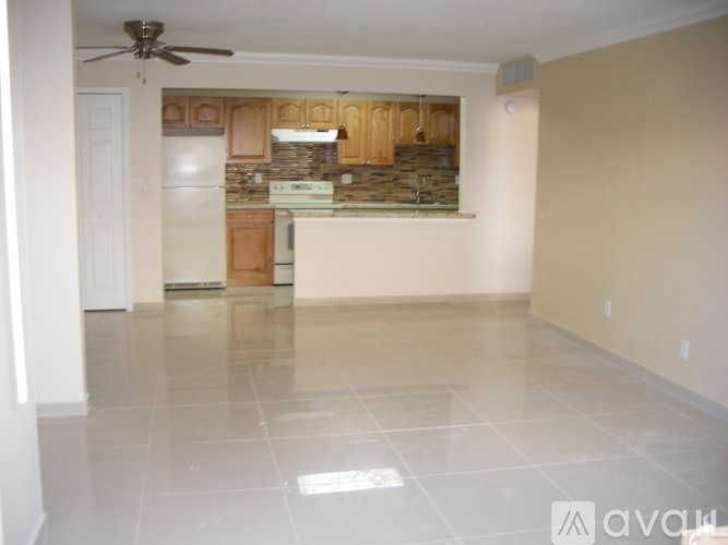 A spacious kitchen with a fan on the ceiling and a refrigerator.
