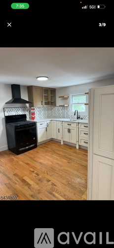 A kitchen with a black stove and wooden floors.