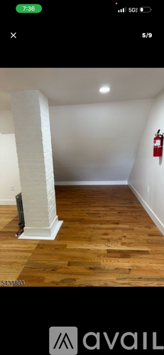 A room with wooden flooring and a white column.