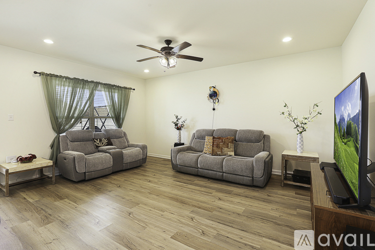 A living room with two grey couches and a television on a wooden stand.