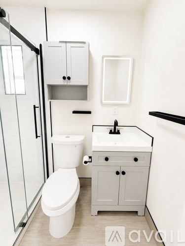 A white toilet sits in a bathroom next to a sink and medicine cabinet.
