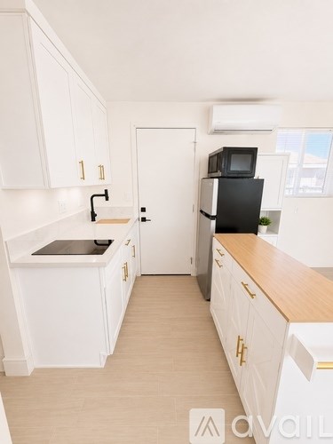 A kitchen with white cabinets and a black fridge.