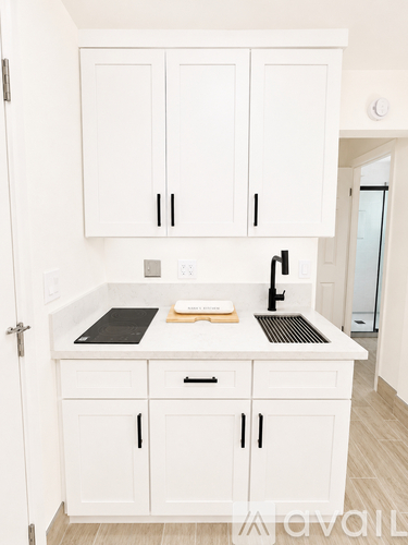 A kitchen with white cabinets and a black countertop.