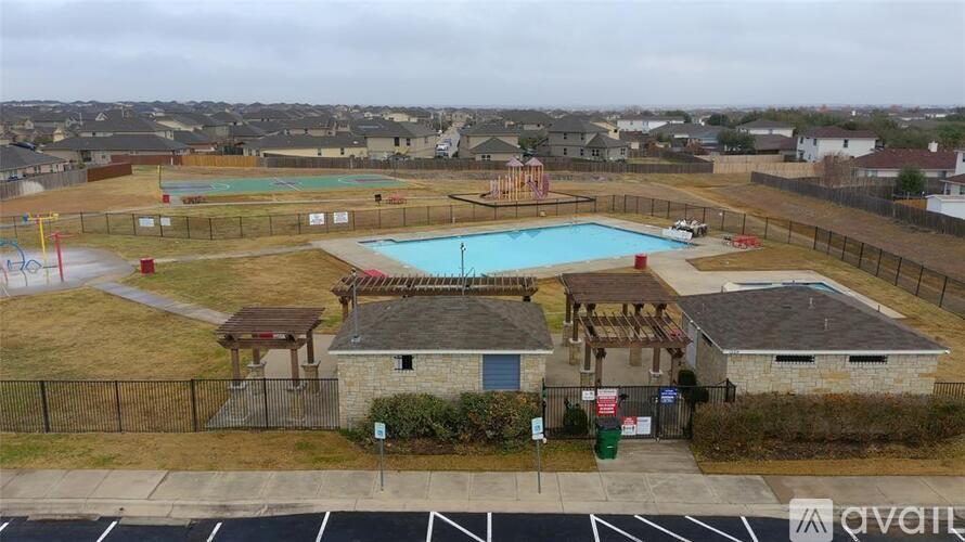 A pool area with a small building and a fence.