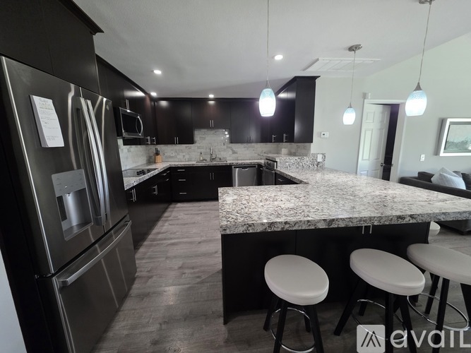 A modern kitchen with black cabinets and granite countertops.