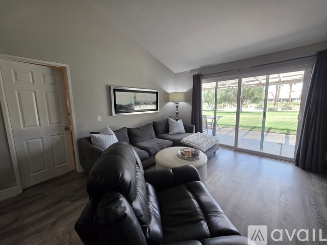 A living room with a black leather couch and a painting on the wall.