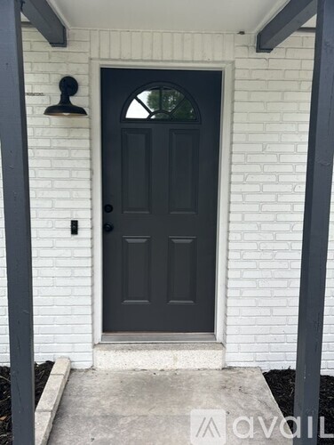 A black door is set in a white brick wall.
