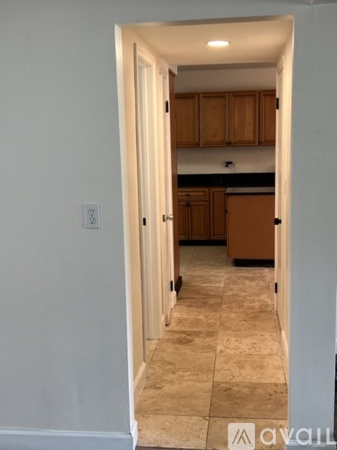 A hallway with a tile floor and a doorway leading to a kitchen.
